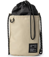 Mini Cross Bag | Bucket Bag - Beige cylindrical bucket bag with black drawstring closure and black rope shoulder straps.