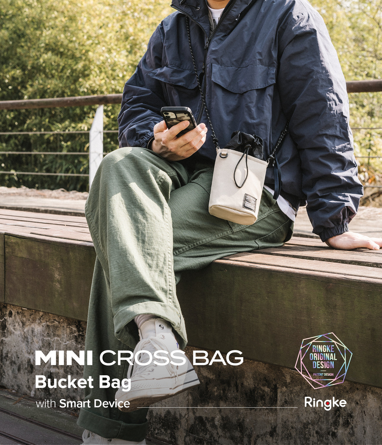 Mini Cross Bag | Bucket Bag - Person sitting on a bench wearing a beige drawstring bucket bag crossbody.