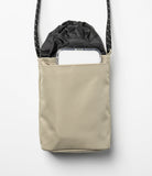 Mini Cross Bag | Bucket Bag - Beige nylon bucket bag with a black drawstring top and a smartphone in the front pocket.
