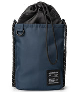 Mini Cross Bag | Bucket Bag - Navy blue drawstring bucket bag with black rope straps and a branded rectangular patch.