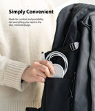 MagSafe Charger Case | Slim - Hand placing a white MagSafe charger into the side pocket of a black backpack.