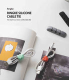 Silicone Cable Tie - Mint and orange silicone ties securing white USB cables on a desk with grey cable organizers.