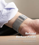 Apple Watch 49·46·45·44 mm | Metal One Mesh - A close-up of a silver metal watch band with a mesh pattern and a rectangular buckle, worn on a person's wrist. The person is wearing a light-colored shirt cuff.