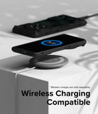OnePlus 12 Case | Fusion-X - A black phone in a rugged case wirelessly charging on a grey pad atop a white block.