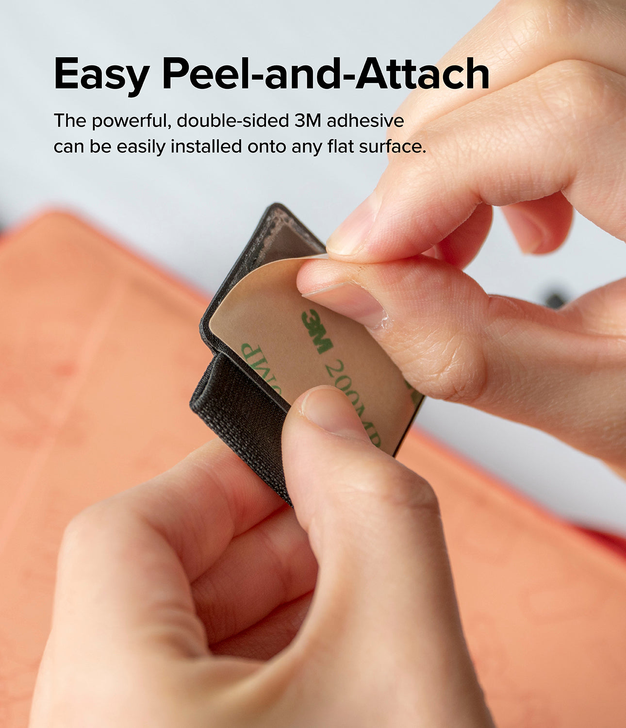 Pen Holder - Hands peeling the protective backing off a black adhesive pen loop to reveal the 3M sticky surface.