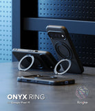 Google Pixel 11 Case | Onyx Ring - Three black phone cases with circular magnetic ring stands are displayed on a dark tabletop against a blue perforated panel background. One case stands upright holding a phone, one lies horizontal, and one is shown folded flat.