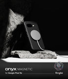 Google Pixel 9a Case | Onyx Magnetic - Black phone case with a magnetic charger attached, resting against a textured rock.