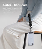 Holder Link Puffer | Hand - Person wearing a black quilted wrist strap attached to a smartphone hanging from their hand.