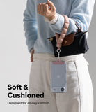Holder Link Puffer | Hand - A person wearing a soft, pink puffer wrist strap attached to a small handbag and a clear phone case.