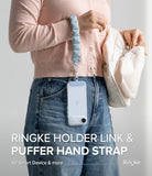 Holder Link Puffer | Hand - Light blue quilted puffer hand strap attached to a clear phone case hanging from a wrist.