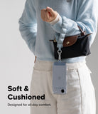 Holder Link Puffer | Hand - A light blue puffer wrist strap attached to a smartphone, hanging from a person's wrist.