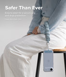 Holder Link Puffer | Hand - A person wears a light blue quilted wrist strap attached to a smartphone hanging from their hand.