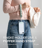 Holder Link Puffer | Hand - A person wearing a sage green quilted puffer hand strap attached to a clear smartphone case.