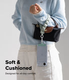 Holder Link Puffer | Hand - A person wearing a light blue sweater holds a puffer wrist strap attached to a phone case.
