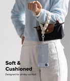 Holder Link Puffer | Hand - A person wearing a soft, white puffer wrist strap attached to a small handbag and a clear phone case.