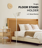 Ringke Stand Floor Holder - A white adjustable floor stand holding a tablet next to a wooden bed frame in a bedroom.