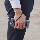 Paracord Lanyard Wrist Strap [2 Pack] - A person holding a smartphone with a black and red paracord wrist strap attached.
