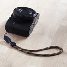 Paracord Lanyard Wrist Strap [2 Pack] - Green camouflage paracord wrist strap attached to a black compact digital camera.