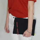 Paracord Lanyard Wrist Strap [2 Pack] - A red and black paracord strap attached to a black zippered pouch held by a person.