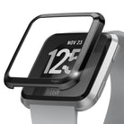 Fitbit Versa | Bezel Styling 03 - Black metal bezel cover hovering above a silver Fitbit Versa smartwatch.