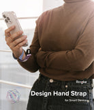 Hand Strap | Basic - Person wearing a brown sweater holds a smartphone secured by a purple fabric wrist strap.