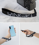Hand Strap | Lettering - Black strap with white Ringke logo text attached to a camera, a smartphone, and a remote control.