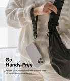 Hand Strap | Basic - A person in a white sweater wears a black camo wrist strap attached to a clear smartphone case.