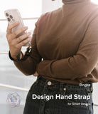 Hand Strap | Basic - Person wearing a brown sweater holding a smartphone secured with a black Ringke hand strap.