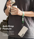 Hand Strap | Basic - A person wearing a green wrist strap attached to a smartphone while holding a coffee mug.