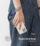 Hand Strap | Lettering - A person wearing a blue and yellow patterned fabric hand strap attached to a smartphone in a clear case.