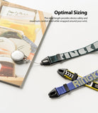 Hand Strap | Lettering - Three colorful patterned wrist straps with black clips arranged on a white surface next to a book.
