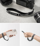 Hand Strap | Lettering - Black wrist strap with white "LIVE A BETTER" text attached to a camera and a smartphone.