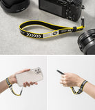 Hand Strap | Lettering - Yellow and black patterned wrist strap attached to a camera, smartphone, and held on a wrist.
