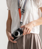 Design Lanyard Strap - Person wearing a grey and orange camera lanyard attached to a vintage-style mirrorless camera.
