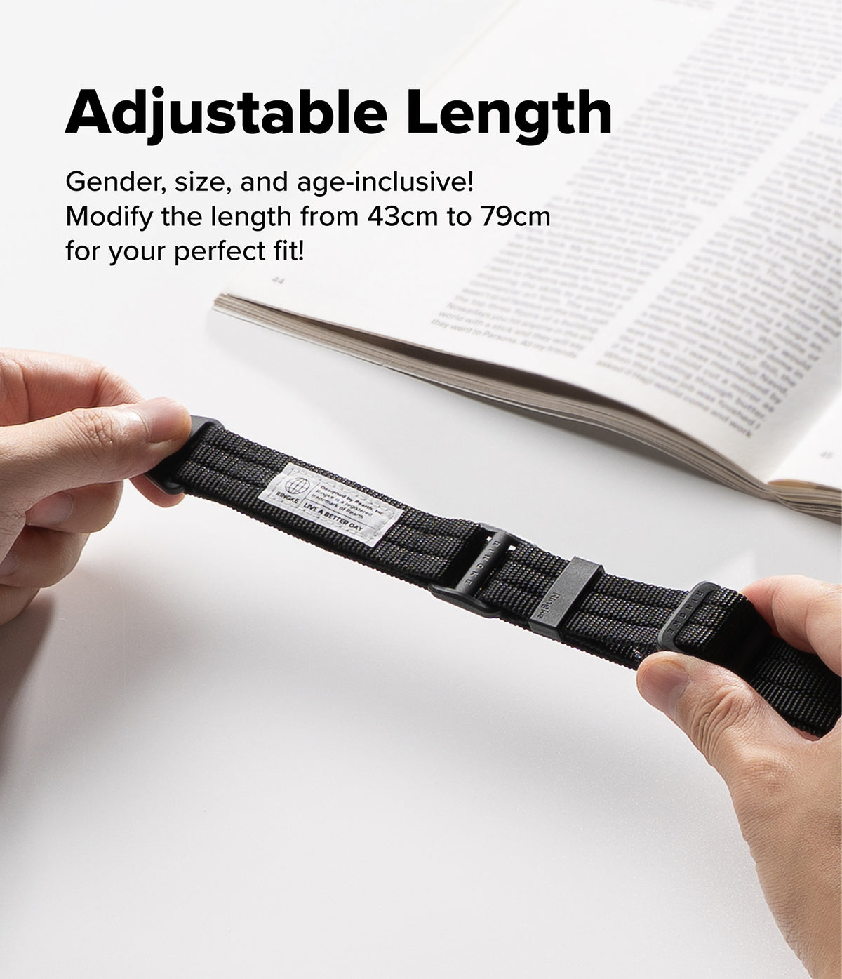 Design Lanyard Strap - A person's hands are shown holding a black adjustable nylon watch strap, stretching it to demonstrate its length-changing feature. An open book is blurred in the background, and bold text at the top reads 'Adjustable Length' with descriptive copy about modifying the length from 43cm to 79cm.