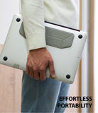 Laptop Stand - A person carries a silver laptop with a slim, gray foldable stand attached to the bottom.