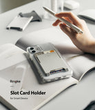 Card Holder | Slot [3 Cards] - A grey Ringke card holder attached to a clear phone case, holding three cards on an open book.