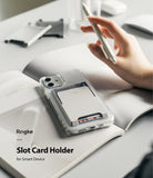 Card Holder | Slot [3 Cards] - A white card holder attached to a clear phone case, holding three cards on an open notebook.
