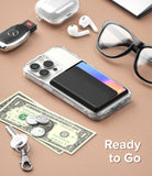 Card Holder | Side Slot - Black card holder attached to a clear phone case, surrounded by daily essentials on a tan surface.