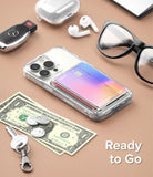 Card Holder | Side Slot - Clear phone case with a colorful card in a side slot, surrounded by everyday items on a tan surface.