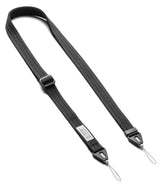 Design Shoulder Strap - A black adjustable camera strap with a textured woven nylon body, featuring a quick-release plastic buckle, a silver metal loop at each end, and a small white brand label.