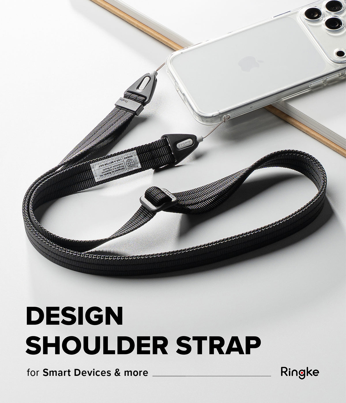 Design Shoulder Strap - A black woven shoulder strap with silver metal hardware, shown draped over a clear smartphone case on a white surface. Text at the bottom reads 'DESIGN SHOULDER STRAP for Smart Devices & more Ringke'.