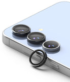 Galaxy S24 FE | Camera Lens Frame Glass - Three black lens protectors on a light blue phone with one detached ring.