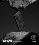 Galaxy S24 FE Case | Onyx - Black camo phone case suspended between two rough, dark stone surfaces in a minimalist studio.