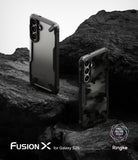 Galaxy S25 Case | Fusion-X - Two Galaxy S25 phones in black Fusion-X cases resting on dark, jagged volcanic rock.