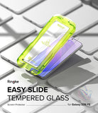 Galaxy S26 FE Screen Protector | Easy Slide Tempered Glass (2P) - Ringke Easy Slide Tempered Glass screen protector shown in a translucent neon green protective sleeve, sliding off a smartphone placed on a white keyboard. Text on the image reads 'Ringke EASY SLIDE TEMPERED GLASS Screen Protector for Galaxy S26 FE'.