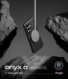 Galaxy S26 Ultra Case | Onyx α Magnetic - Black phone case suspended by a magnetic charger between dark stone rocks.