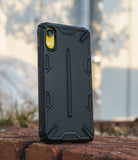 iPhone XR Case | Dual-X [DX] - Matte black rugged protective phone case with geometric accents standing on a brick surface.