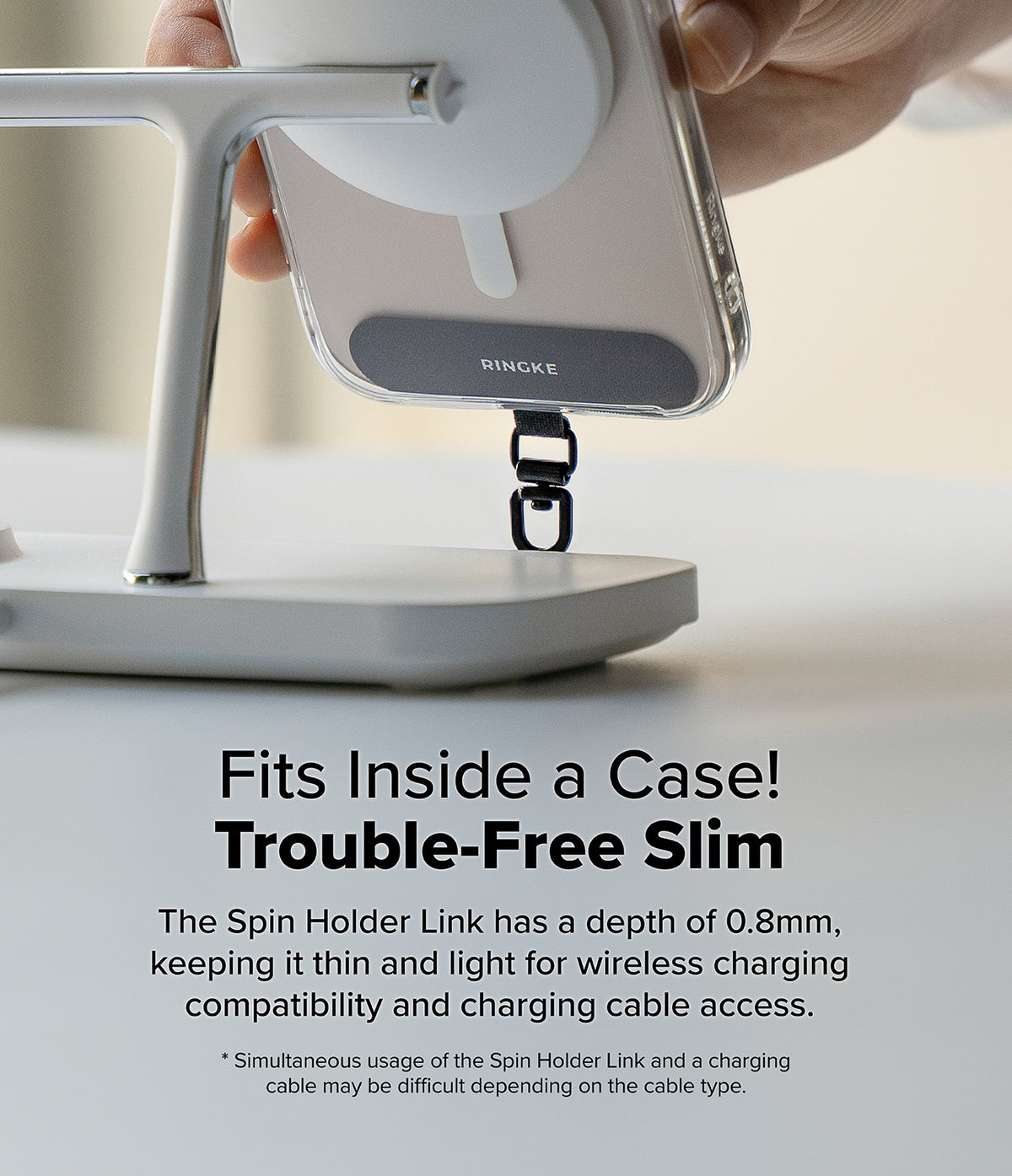 Holder Link Spin - A slim Ringke phone strap attachment installed inside a clear case on a wireless charging stand.