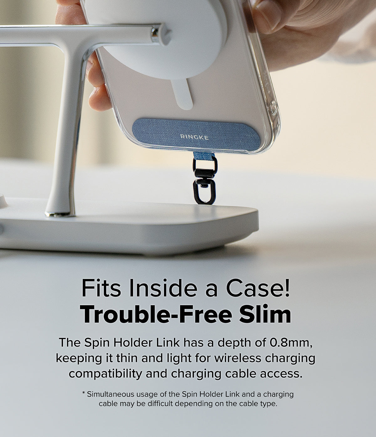 Holder Link Spin - A blue Ringke phone strap attachment mounted on a phone case while charging on a wireless stand.